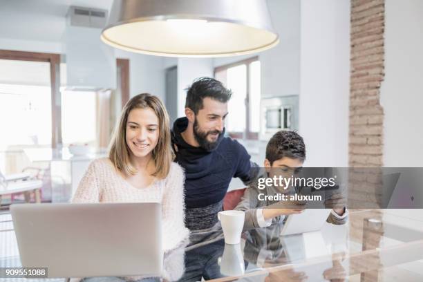 family using laptop and tablet in the kitchen - mother and son using tablet and laptop stock pictures, royalty-free photos & images