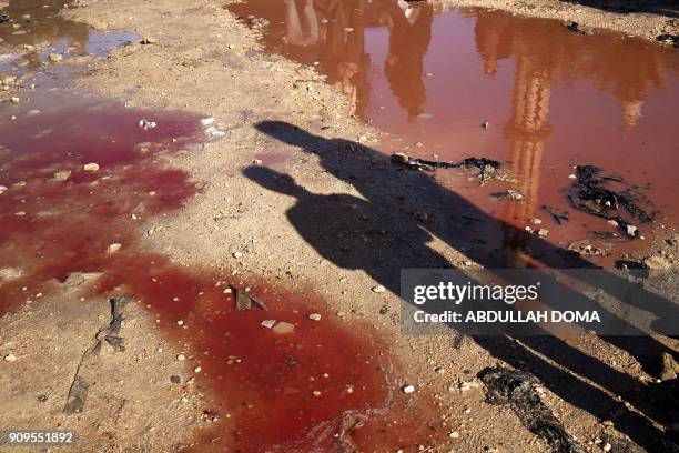 Libyans check the aftermath of an explosion in the eastern city of Benghazi on January 24, 2018. - The death toll following a double car bomb attack...