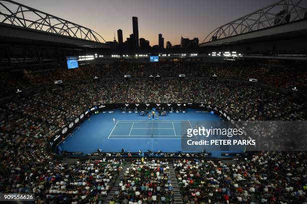 As the sun sets behind the city skyline, Switzerland's Roger Federer plays against Czech Republic's Tomas Berdych during their men's singles...