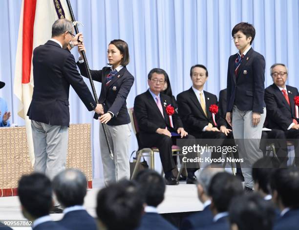 Ski jumper Sara Takanashi receives the Japan flag from Yasuo Saito , one of the vice presidents of the Japanese Olympic Committee, during an...