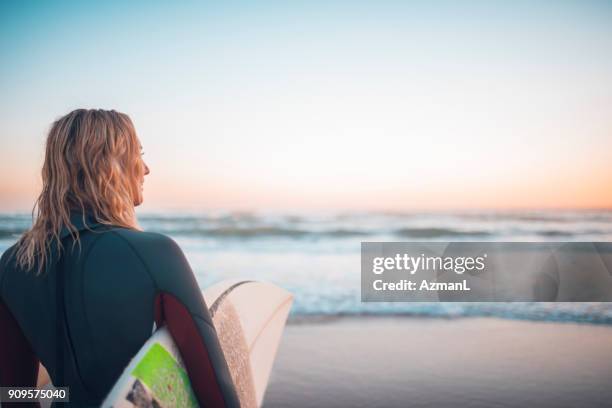 young woman getting ready for surfing - queensland people stock pictures, royalty-free photos & images