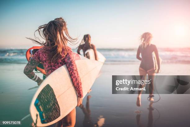 vrienden in de oceaan met hun surfplanken - woman surfboard stockfoto's en -beelden