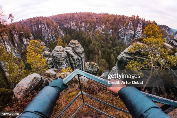 guy from personal perspective doing hiking and contemplating from viewpoint the beautiful saxon national park in germany with stunning views of the rock formations with vertigo and adrenaline sensations. - vertigo foto e immagini stock