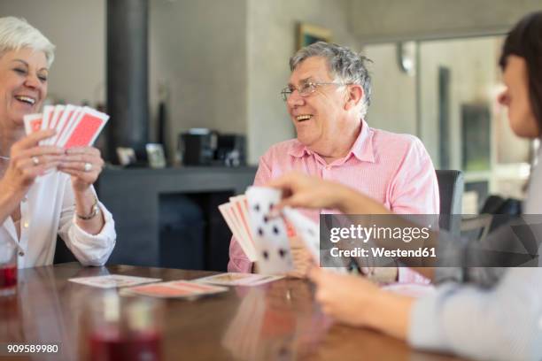 senior couple playing cards with daughter at home - card game mature people stock-fotos und bilder