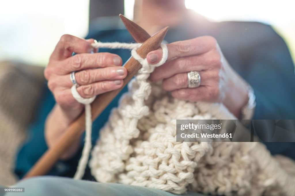 Senior woman knitting on couch at home