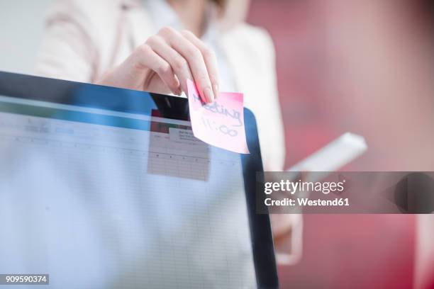 woman putting sticky note on computer screen in office - sticky-notes-covering-computer-monitor stock pictures, royalty-free photos & images