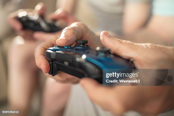 close-up of hand holding video game controller - manette de jeu vidéo photos et images de collection