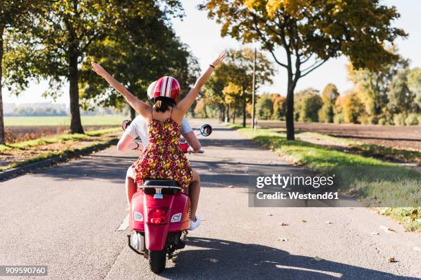 carefree young couple riding motor scooter on country road - lambreta imagens e fotografias de stock