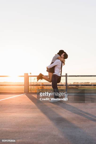 young couple hugging on parking level at sunset - young couple kiss ストックフォトと画像