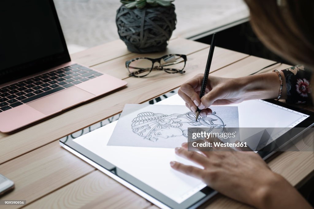 Woman's hand drawing template on light table