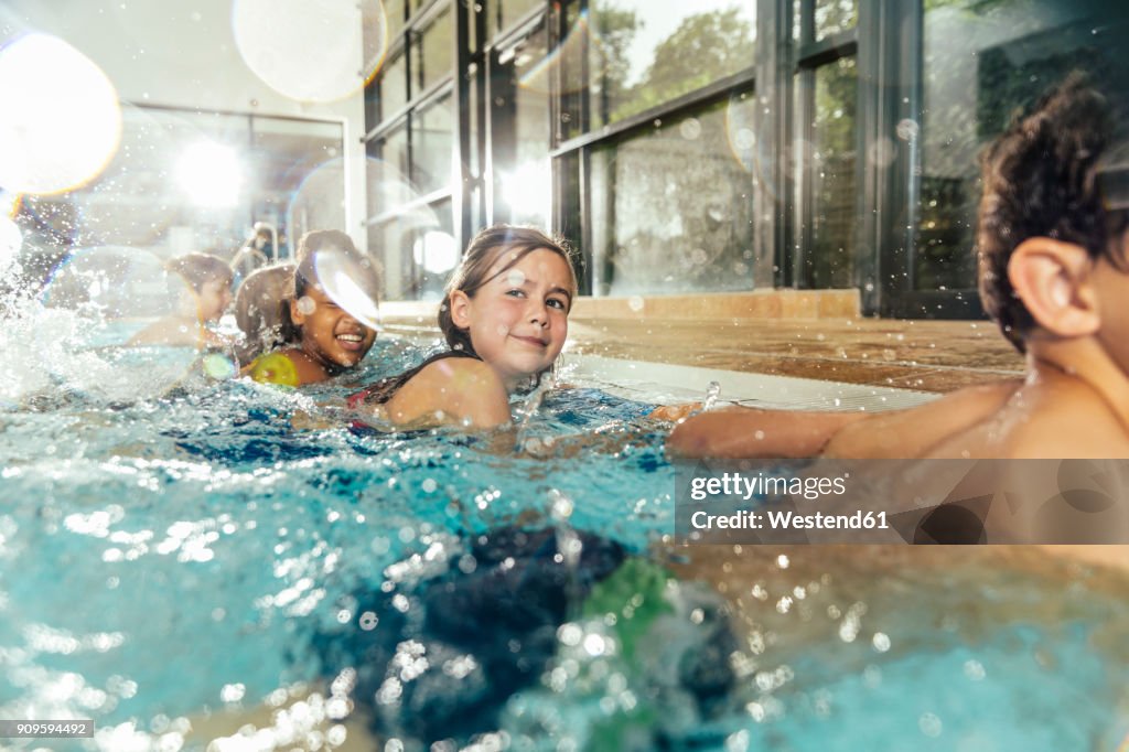 Children in swimming class practicing at poolside in indoor swimming pool