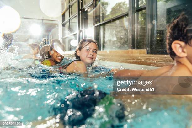 children in swimming class practicing at poolside in indoor swimming pool - niño bañandose fotografías e imágenes de stock