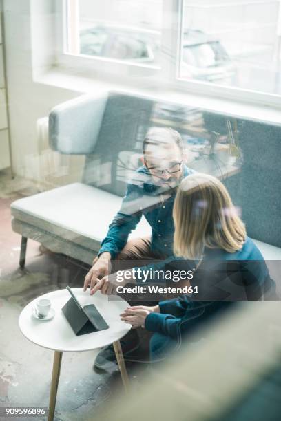 businessman and businesswoman with tablet discussing in office lounge - lounge room stock-fotos und bilder