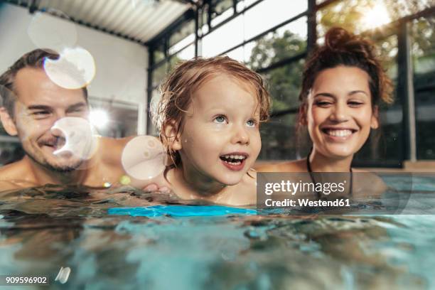 happy parents with daughter in indoor swimming pool - hallenbad stock-fotos und bilder