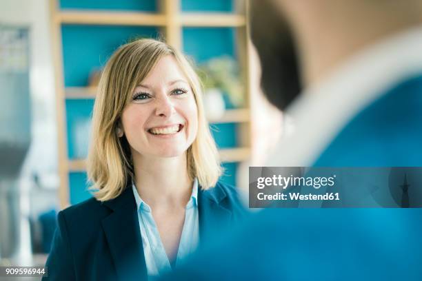 businesswoman smiling at businessman in office - portrait woman men looking at each other stock-fotos und bilder