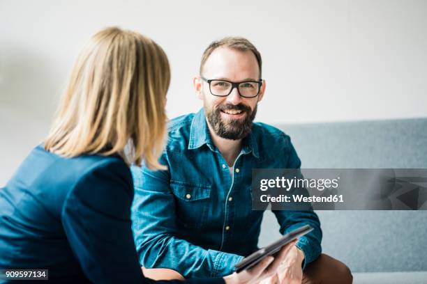 smiling businessman and businesswoman in office lounge - gespräch zwei personen stock-fotos und bilder