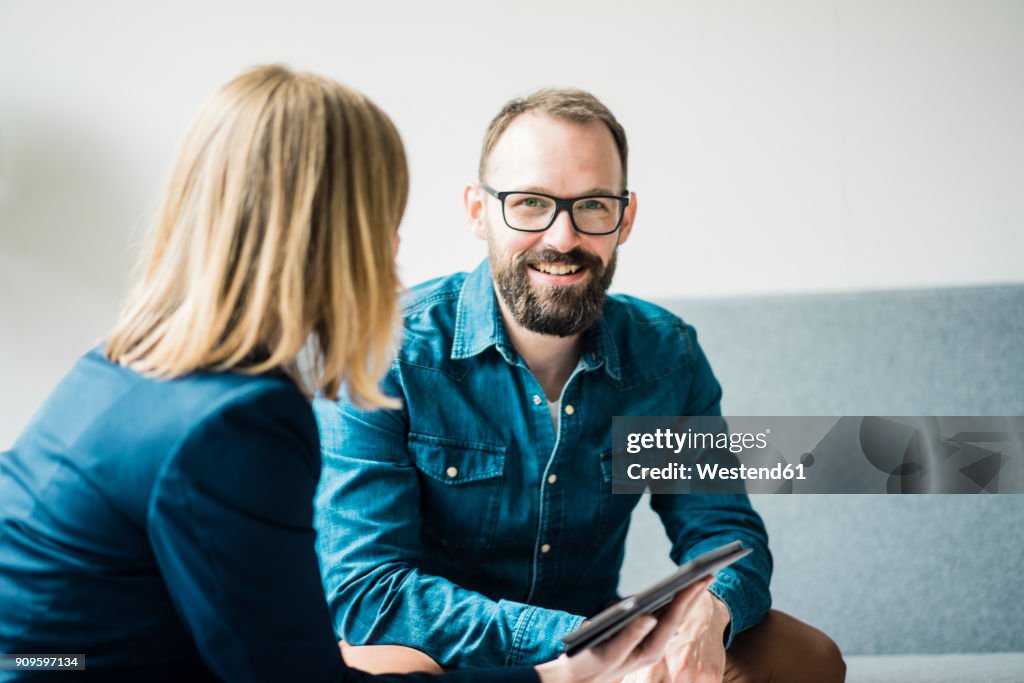 Smiling businessman and businesswoman in office lounge