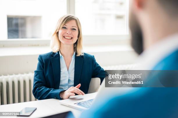 businesswoman smiling at businessman in office - phone interview event stock pictures, royalty-free photos & images