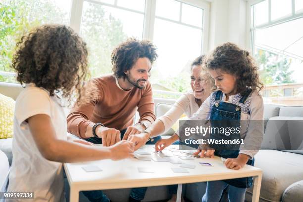 family sitting on couch , playing memory game - jeu de société photos et images de collection