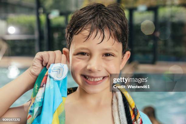 portrait of proud boy showing his swimming badge at the poolside of an indoor swimming pool - awards inside stockfoto's en -beelden