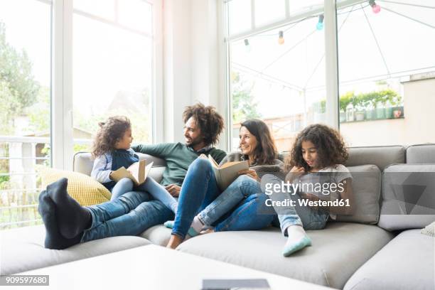 happy family sitting on couch, reading books - family couch bildbanksfoton och bilder
