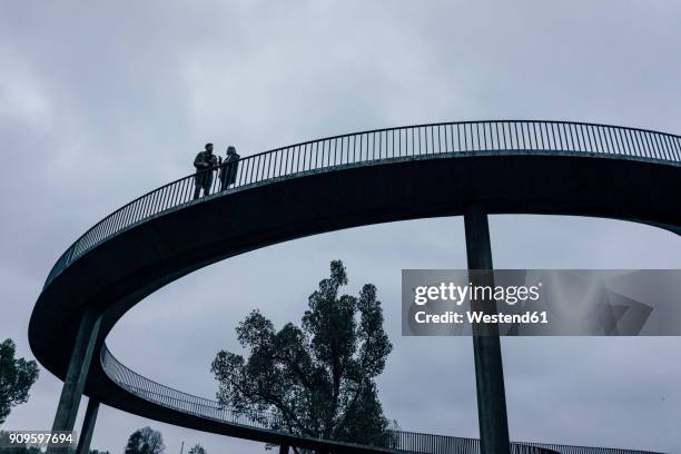 two businessmen standing on dark bridge, having a meeting - father son business europe stock-fotos und bilder