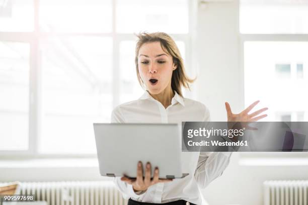 amazed woman holding laptop - faszination stock-fotos und bilder