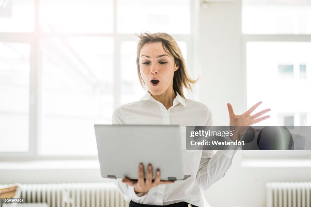 Amazed woman holding laptop