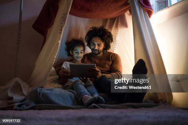 father and daughter sitting in dark children's room, looking at digital tablet - rapariga no quarto tecnologia imagens e fotografias de stock