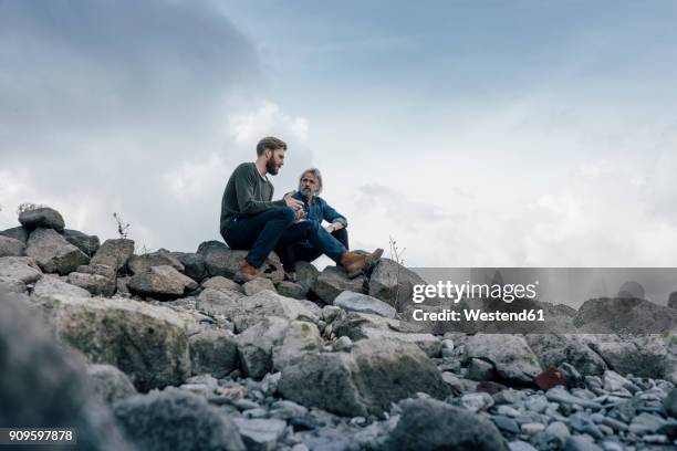 father and son spending time together outdoors, taking a break, sitting on stones - father son admiration stock pictures, royalty-free photos & images