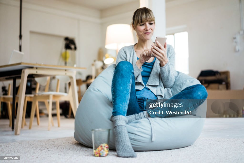 Smiling woman sitting in beanbag using cell phone