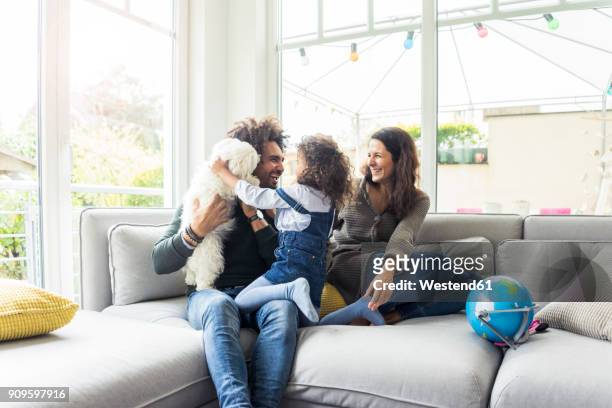 happy family with dog sitting together in cozy living room - pets fotografías e imágenes de stock