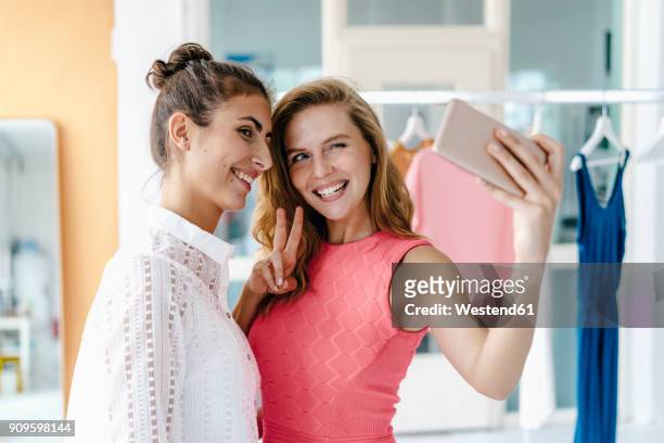 two smiling young women taking a selfie in fashion studio - fashion blogger stock-fotos und bilder