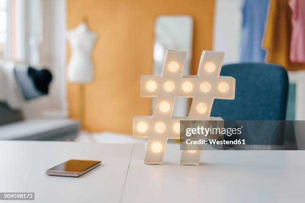 illuminated hashtag sign on table in fashion studio - hashtag foto e immagini stock