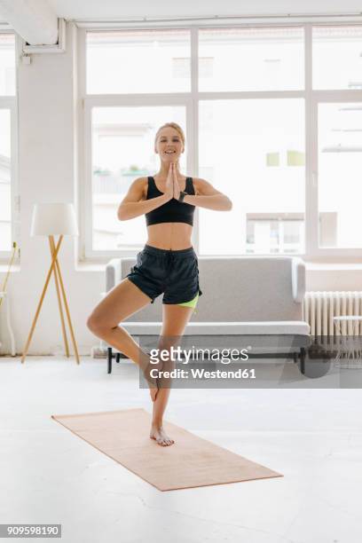 smiling young woman practising yoga - standing on one leg fotografías e imágenes de stock