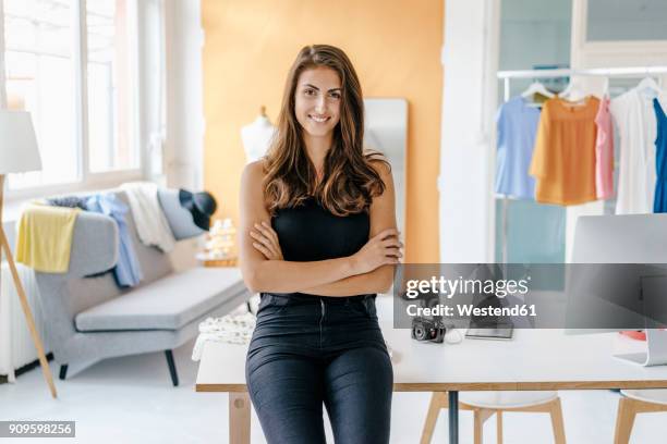 portrait of smiling young woman in fashion studio with camera on table - tech founder stock pictures, royalty-free photos & images