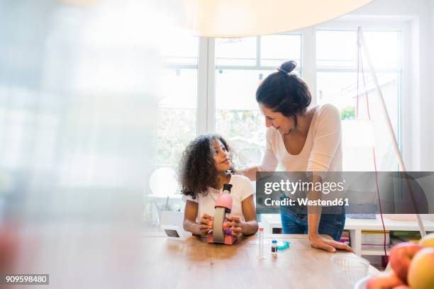 mother helping daughter with homework, using microscope - young girls homework stock-fotos und bilder