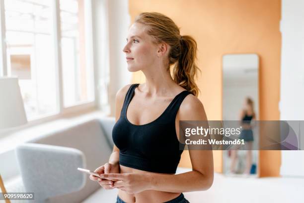young woman in sportswear holding cell phone - sportswear stock pictures, royalty-free photos & images