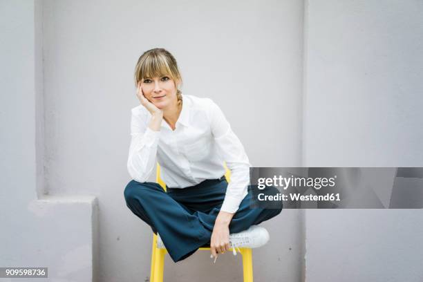 portrait of woman sitting on a chair - gambe incrociate foto e immagini stock