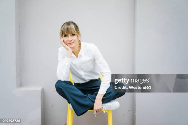portrait of woman sitting on a chair - mano sul mento foto e immagini stock