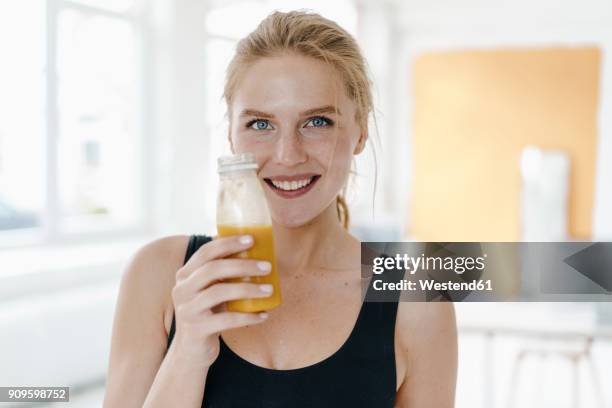 portrait of smiling young woman in sportswear drinking a smoothie - sport drinking bottle stock-fotos und bilder