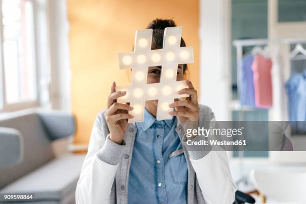 young woman hiding behind hashtag sign in studio - blogger woman stockfoto's en -beelden