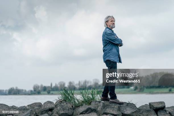 senior man standing on stones looking at rhine river - wind river film 2017 stock-fotos und bilder