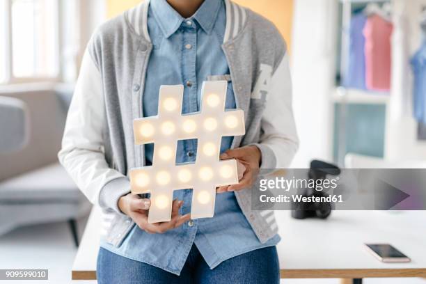 young woman holding hashtag sign in studio - hashtag ストックフォトと画像