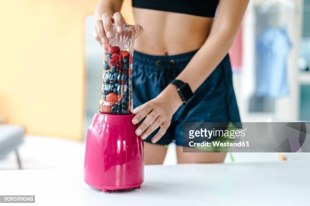 young woman in sportswear blending fruit - robot da cucina foto e immagini stock