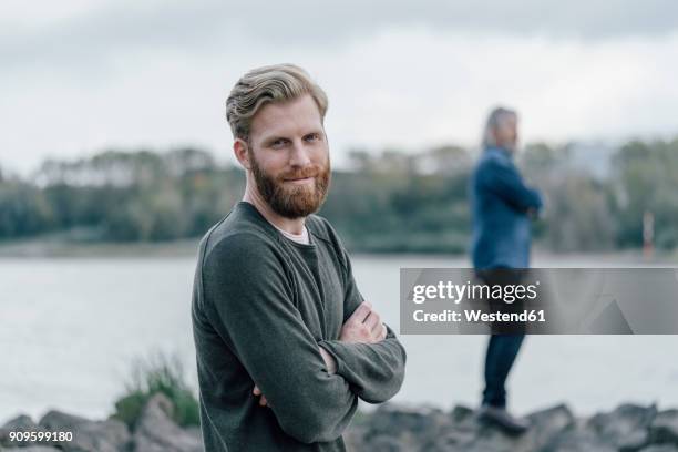 father and son spending time together ath the river, father standing on rocks - appreciation stock-fotos und bilder