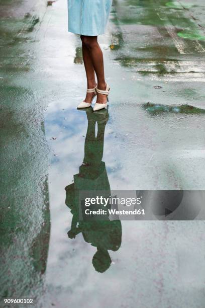 usa, new york, young african-american woman standing on street, high heels, water reflection in puddle - puddle reflection stock pictures, royalty-free photos & images