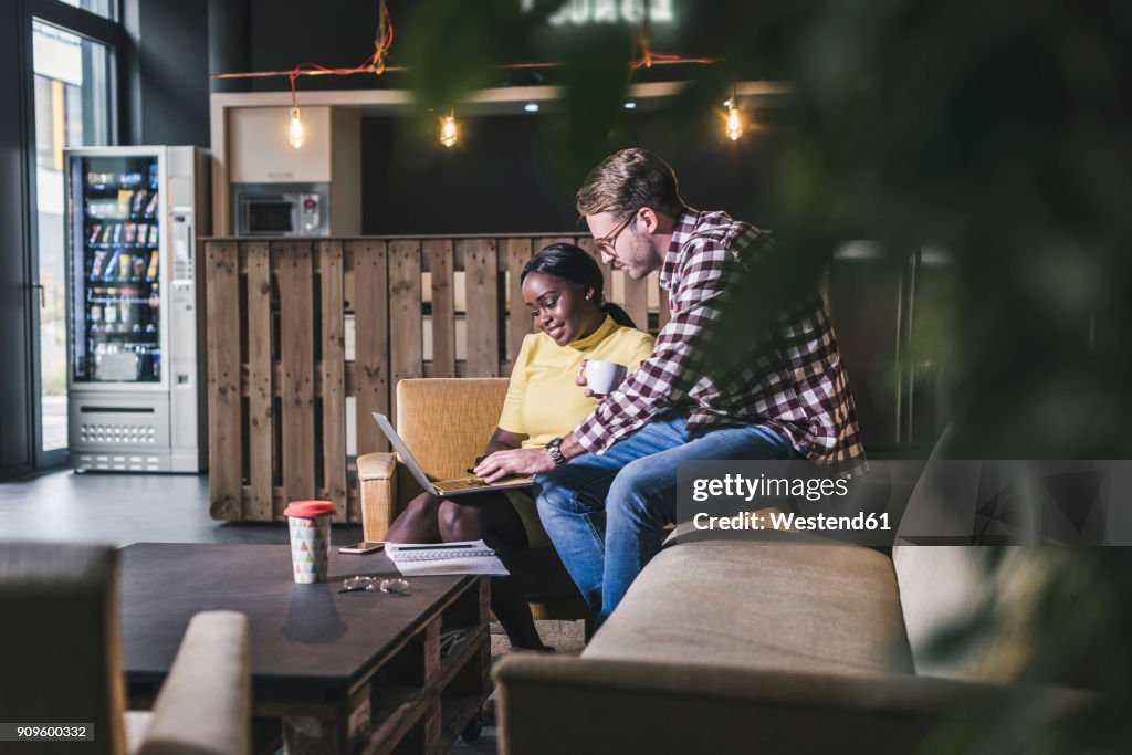 Colleagues working together on laptop in a cafe