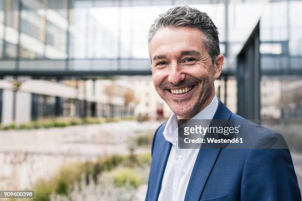 portrait of smiling businessman outside office building - white business suit stock pictures, royalty-free photos & images