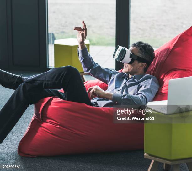 man sitting in beanbag wearing vr glasses - bean bag stock-fotos und bilder